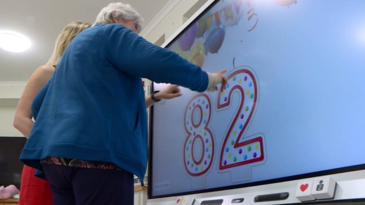 A senior from Port Macquarie elderly care facility taking part in an interactive activity on a SMART Board.
