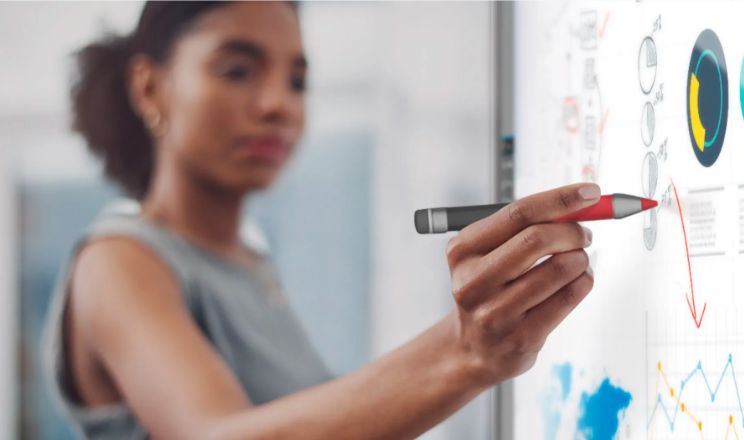 A focused businesswoman using a SMART Interactive display for data analysis, representing the efficiency of SMART technology in accelerating business operations.